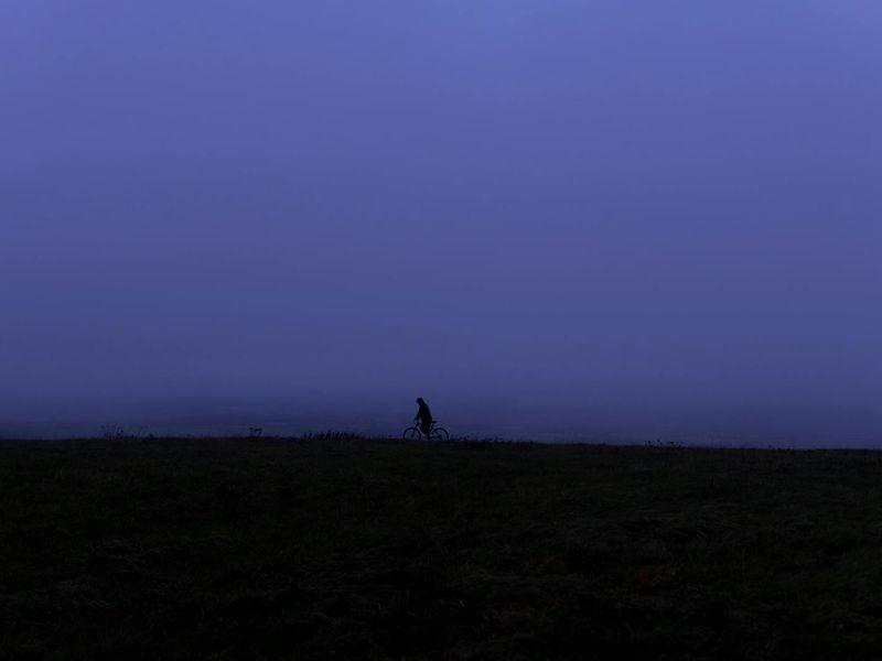 Person performing a gentle stretching exercise in a calm, dark room.